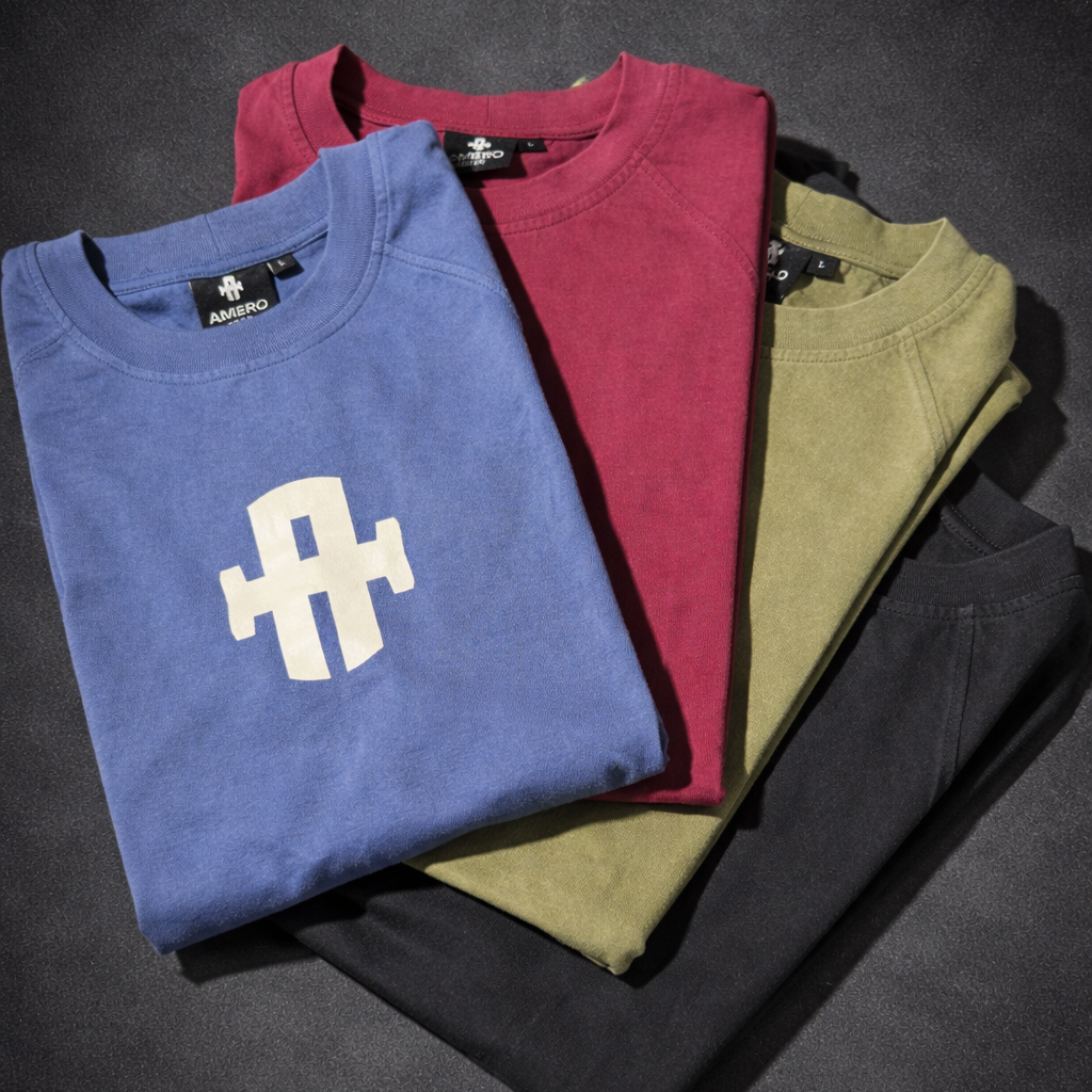 Amero Gear Folded t-shirts in blue, red, green, and black on a dark surface