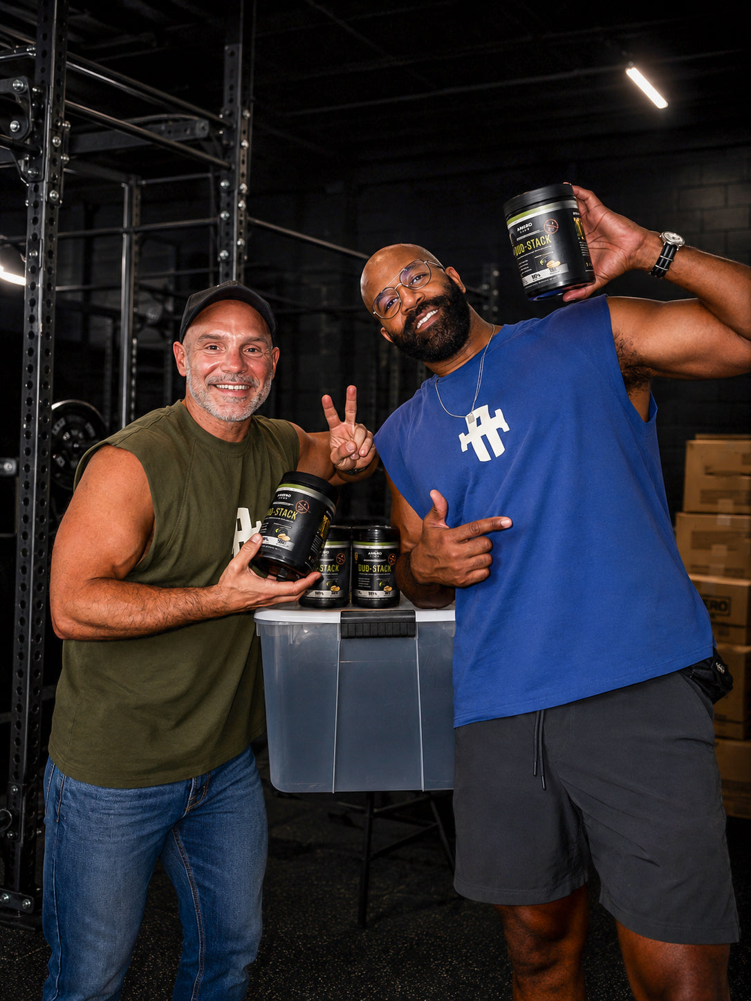 Amery Moultry & Roberto Buckley, founders of Amero Gear Two men holding supplement containers in a warehouse setting
