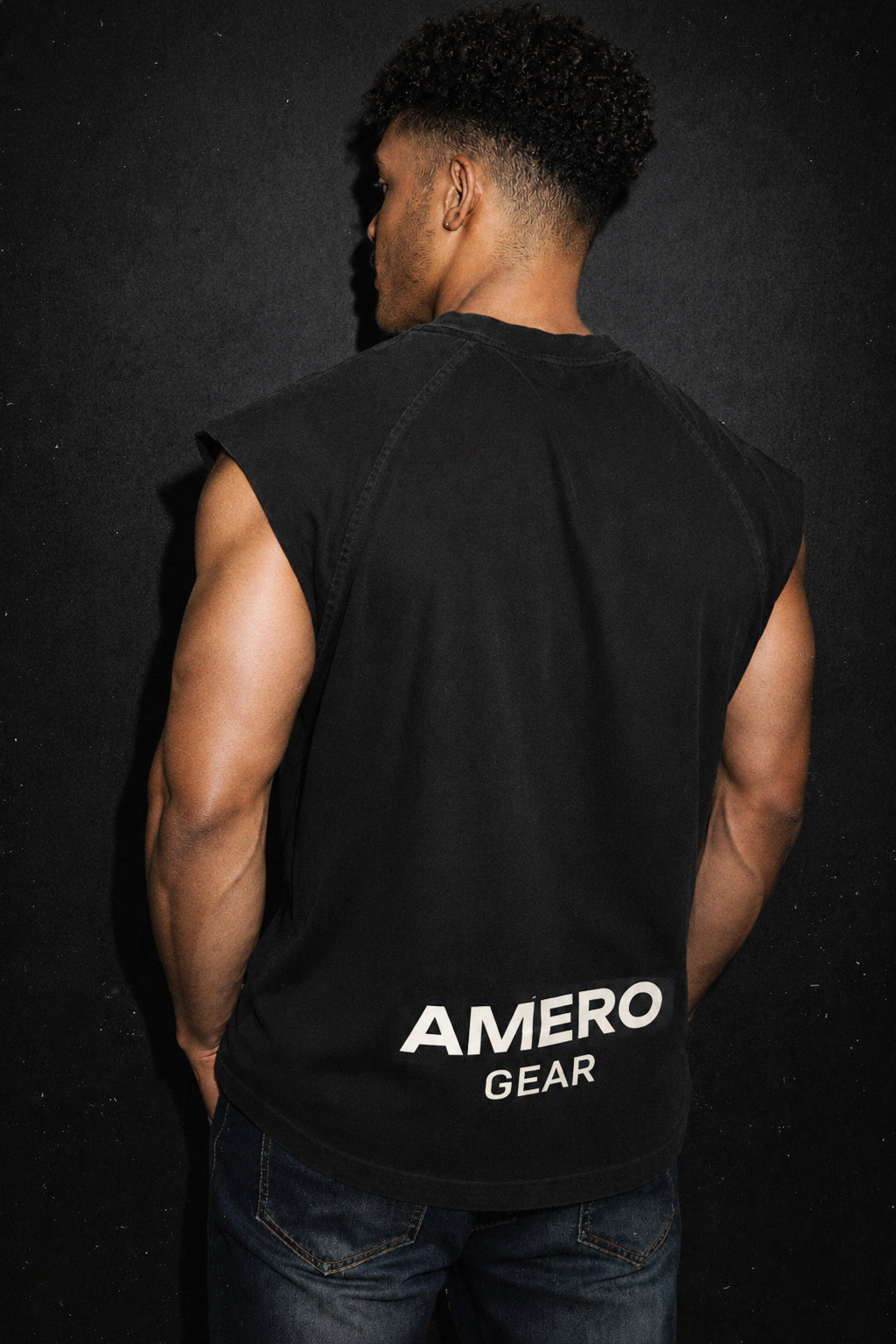 Person wearing a black sleeveless shirt with 'AMERO GEAR' branding on the back against a dark background