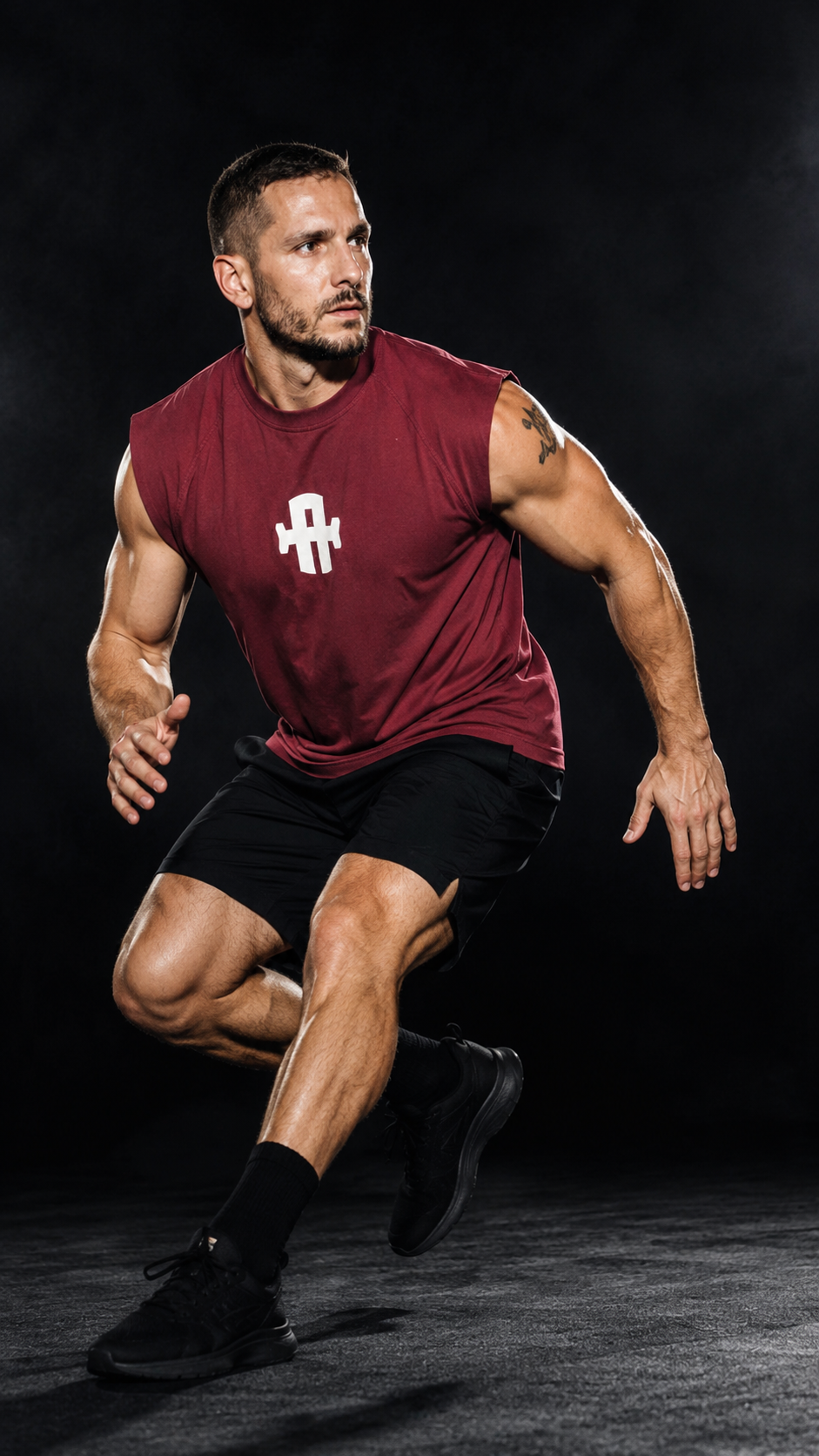 Athlete in maroon sleeveless shirt and black shorts running on a dark background
