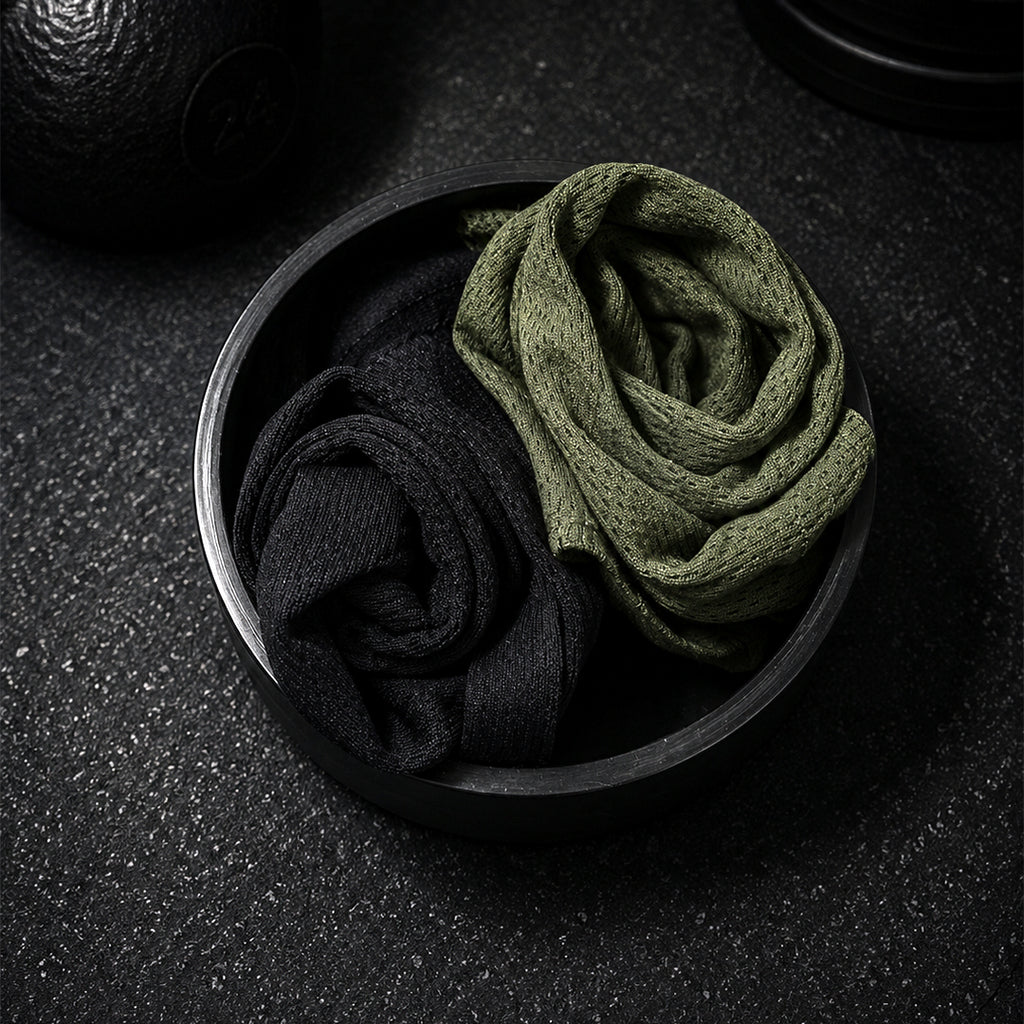 Two pairs of socks, one black and one green, in a metal bowl on a dark textured surface.