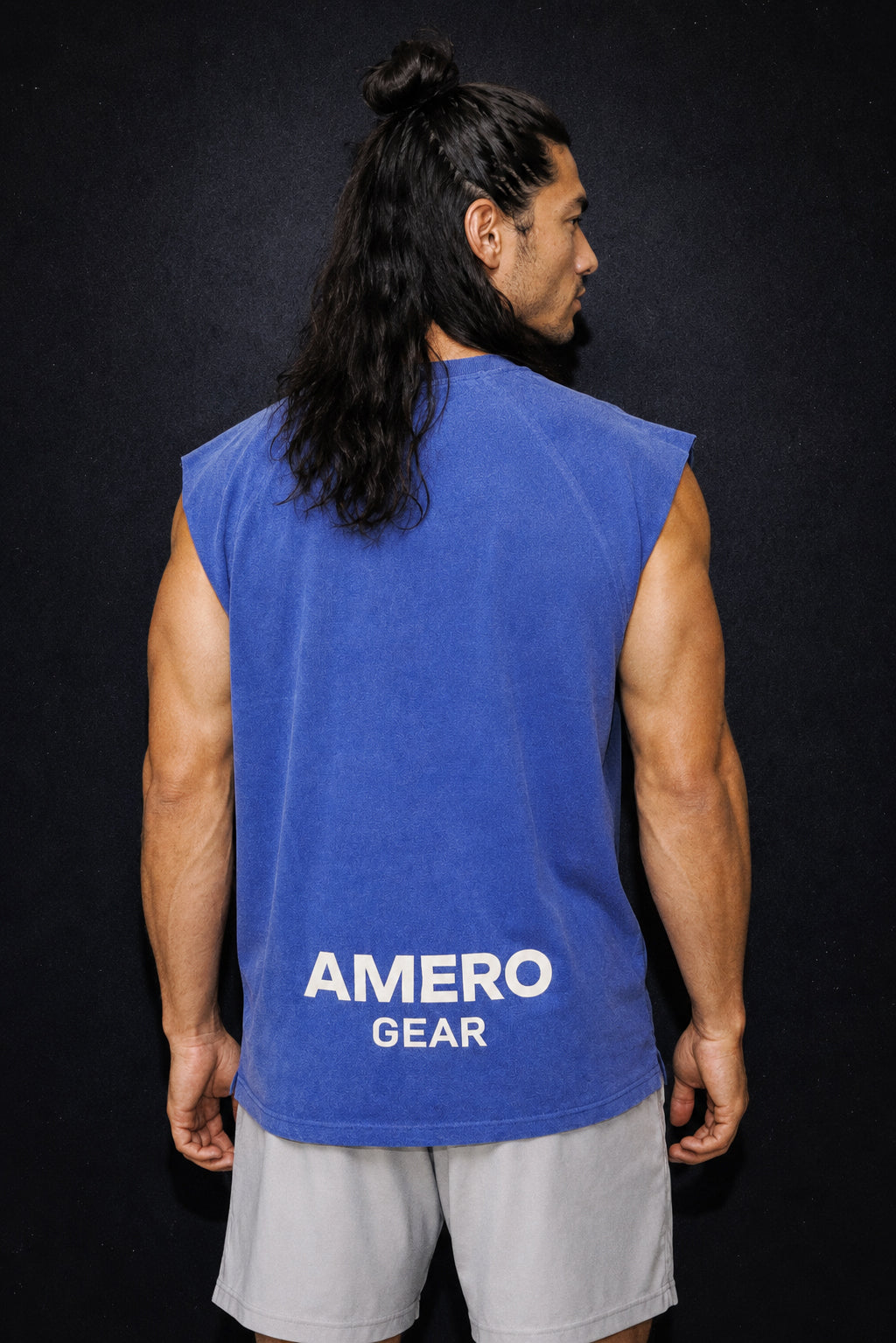 Person wearing a blue sleeveless shirt with 'AMERO GEAR' branding on the back against a black background