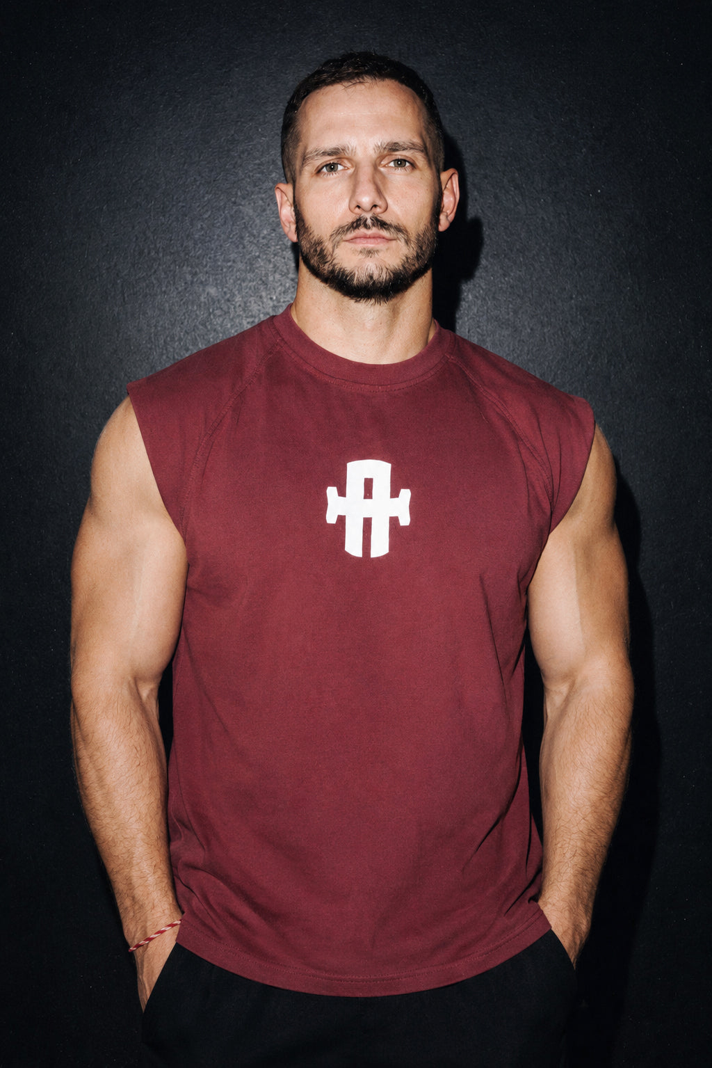 Man wearing a maroon sleeveless shirt with a white logo on a black background