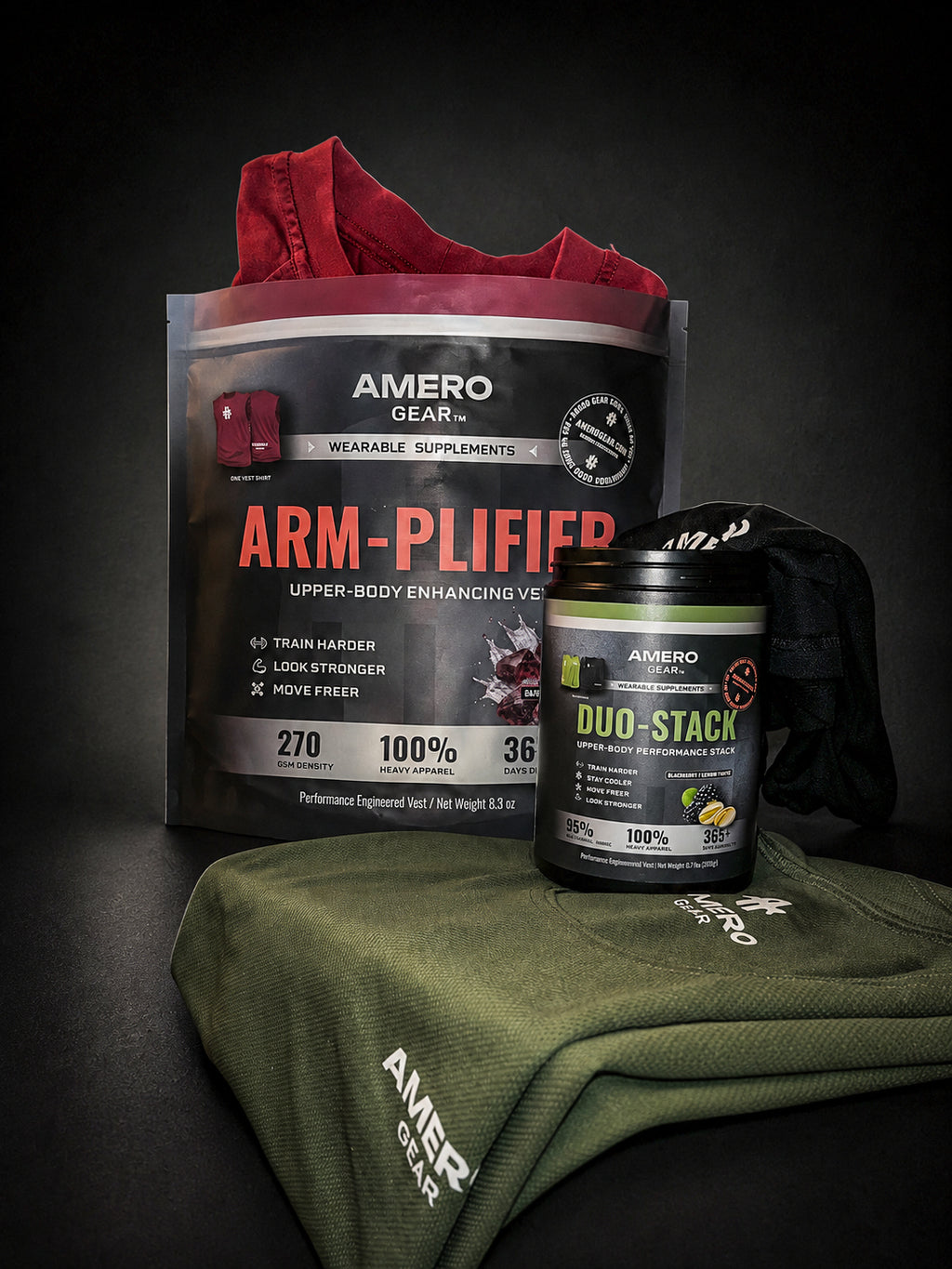 A product bundle from Amero Gear featuring a large black and red 'Arm-Plifier' supplement bag, a black and green 'Duo-Stack' protein powder tub, and an olive green t-shirt with white branding, arranged on a dark background.